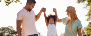 Parents et enfant complices en plein air, illustrant l'épargne et la prévoyance familiale.