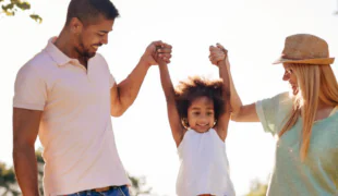 Parents et enfant complices en plein air, illustrant l'épargne et la prévoyance familiale.