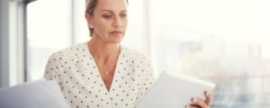 Dirigeante d'entreprise consultant une tablette pour optimiser la fiscalité de la cession de son entreprise avant la retraite.