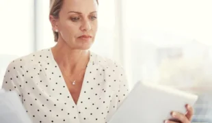 Dirigeante d'entreprise consultant une tablette pour optimiser la fiscalité de la cession de son entreprise avant la retraite.